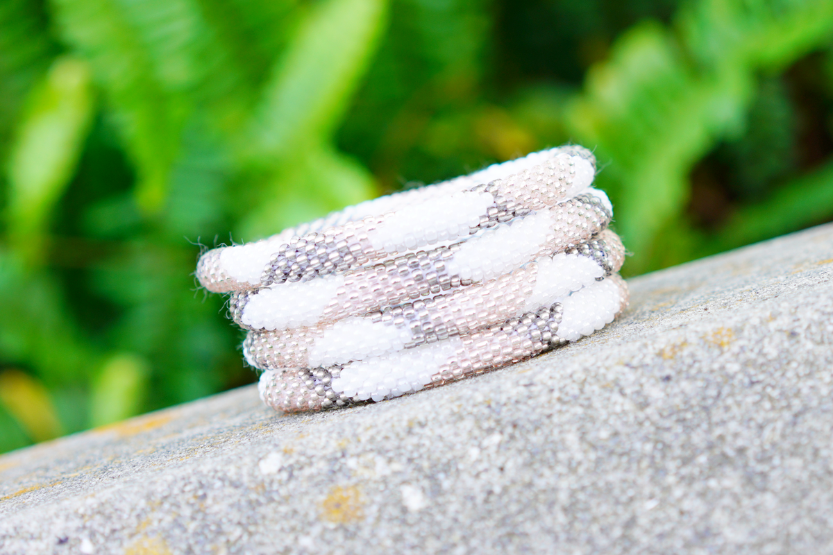 Sashka Co handmade beaded friendship bracelet with white, rose gold, and silver glass beads. Crafted in Nepal by skilled artisans in a large diamond pattern.