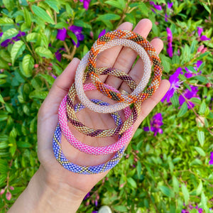 Hand holding 5 different colorful sashka co. glass beaded bracelets