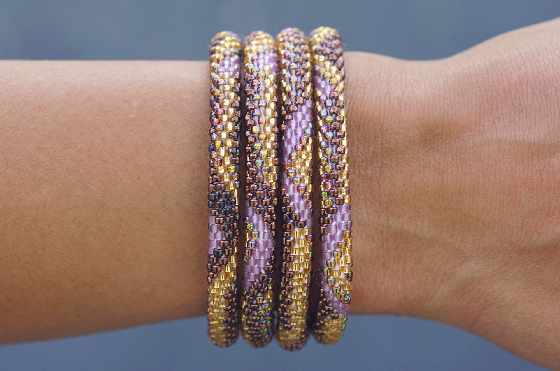 Sashka Co. handmade glass beaded friendship bracelet with brown, purple, and gold glass beads in a zigzag zipper pattern. Crafted in Nepal by skilled artisans.