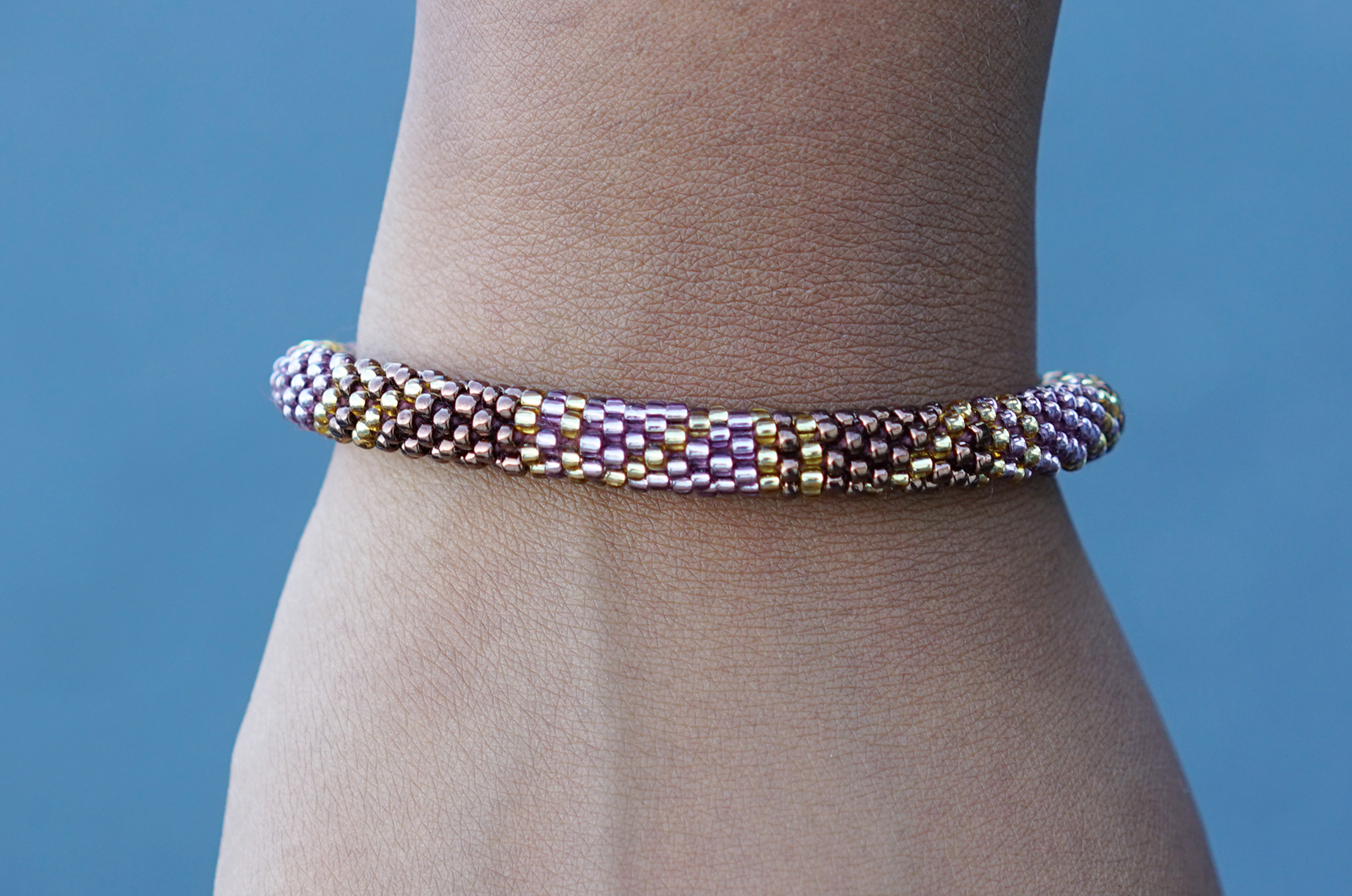 Sashka Co. handmade glass beaded friendship bracelet with brown, purple, and gold glass beads in a block spiral pattern. Crafted in Nepal by skilled artisans.