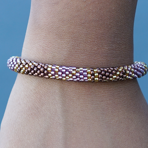 Sashka Co. handmade glass beaded friendship bracelet with brown, purple, and gold glass beads in a block spiral pattern. Crafted in Nepal by skilled artisans.