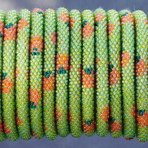 Sashka Co. handmade glass beaded friendship bracelet with iridescent green, orange, and green glass beads in an orange pattern. Crafted in Nepal by skilled artisans.