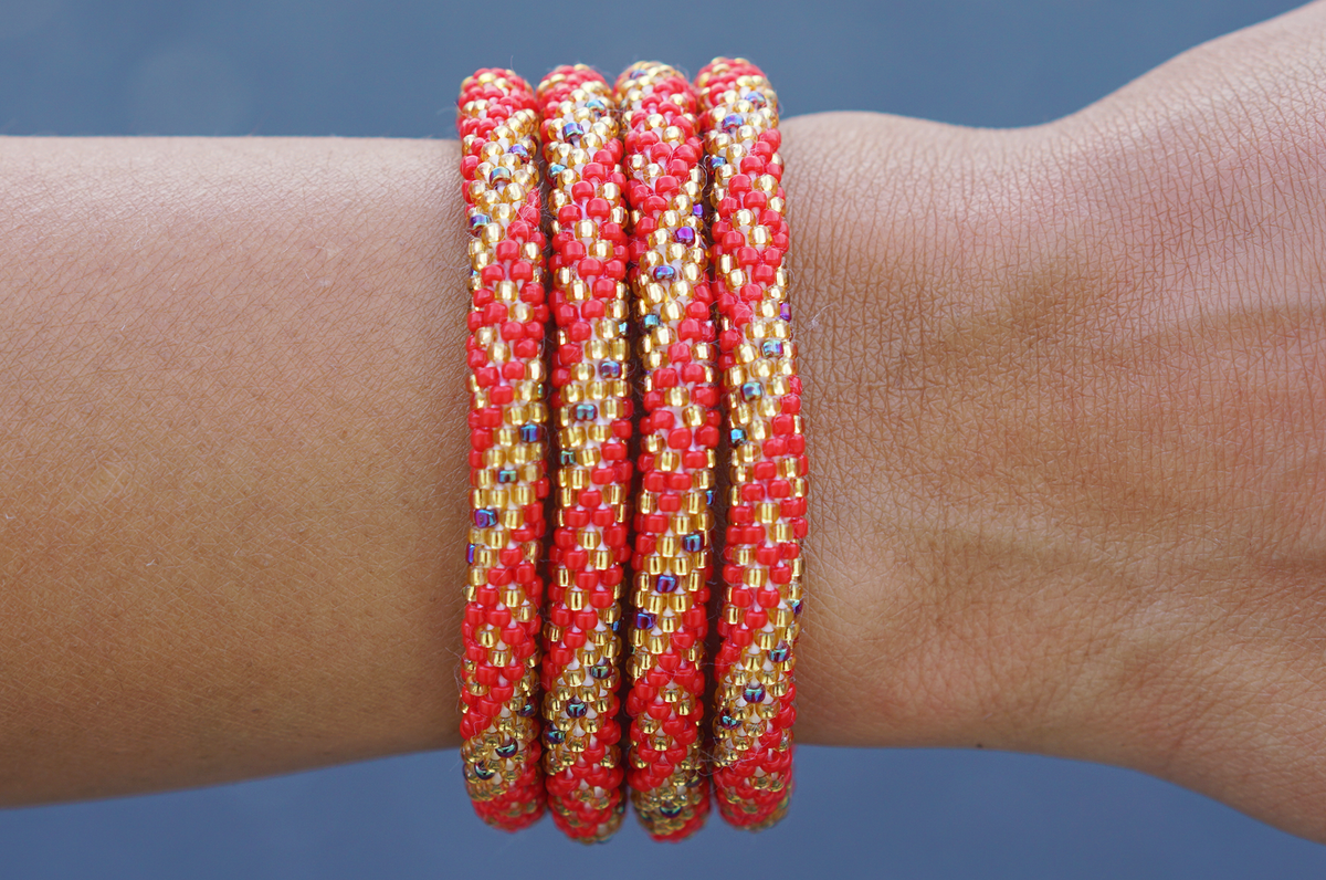 Sashka Co. handmade glass beaded friendship bracelet with red, iridescent, and gold glass beads in a spiral dots pattern. Crafted in Nepal by skilled artisans.