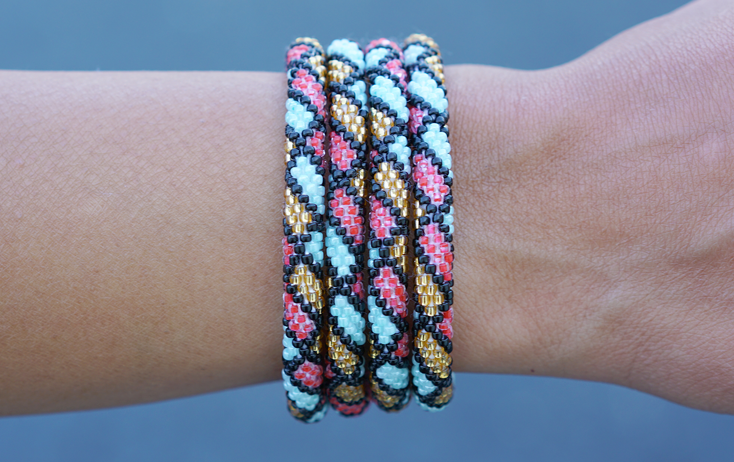 Sashka Co handmade beaded friendship bracelet with black, mint, red, and gold glass beads. Crafted in Nepal by skilled artisans in a lace pattern.
