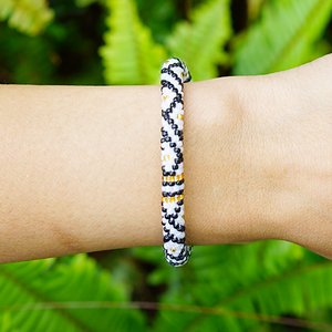 Sashka Co handmade beaded friendship bracelet with black, white, and gold glass beads. Crafted in Nepal by skilled artisans in a diamond pattern.