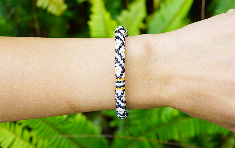 Sashka Co handmade beaded friendship bracelet with black, white, and gold glass beads. Crafted in Nepal by skilled artisans in a diamond pattern.