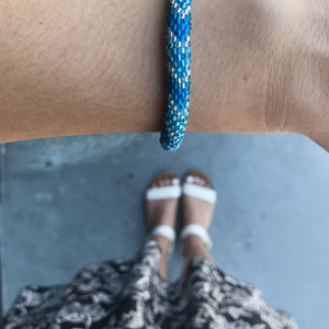Sashka Co handmade beaded friendship bracelet with blue, metallic blue, and clear glass beads. Crafted in Nepal by skilled artisans in a chevron pattern.