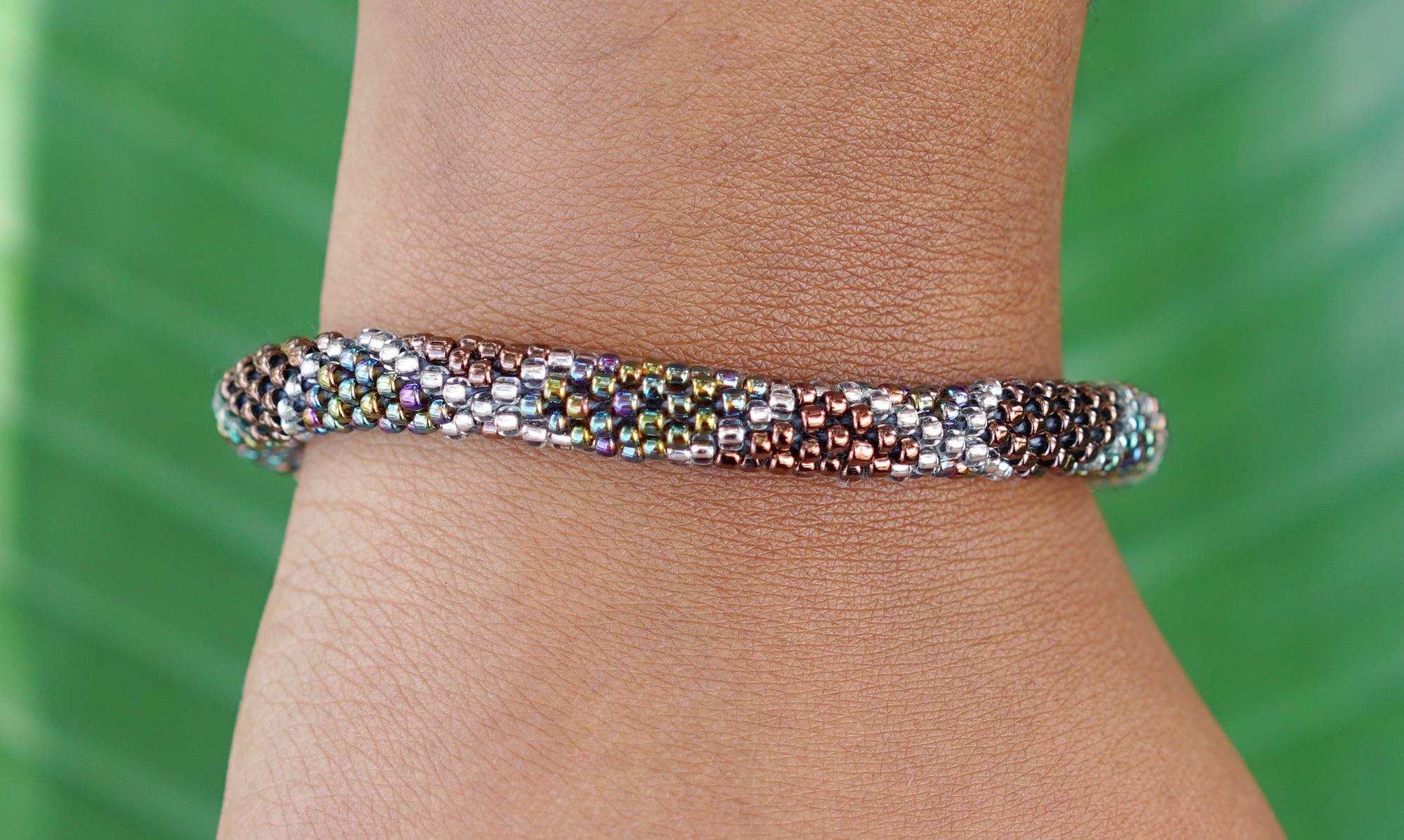 Sashka Co handmade beaded friendship bracelet with iridescent brown, clear, and iridescent glass beads. Crafted in Nepal by skilled artisans in a criss cross pattern.