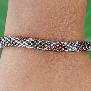 Sashka Co handmade beaded friendship bracelet with iridescent brown, clear, and iridescent glass beads. Crafted in Nepal by skilled artisans in a criss cross pattern.