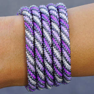 Sashka Co handmade beaded friendship bracelet with matte purple, iridescent purple, clear, and silver glass beads. Crafted in Nepal by skilled artisans in a spiral pattern.