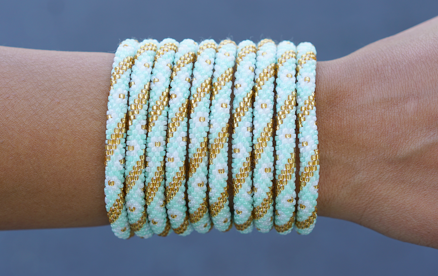 Sashka Co handmade beaded friendship bracelet with mint, white, and gold glass beads. Crafted in Nepal by skilled artisans in a flower spiral pattern.


