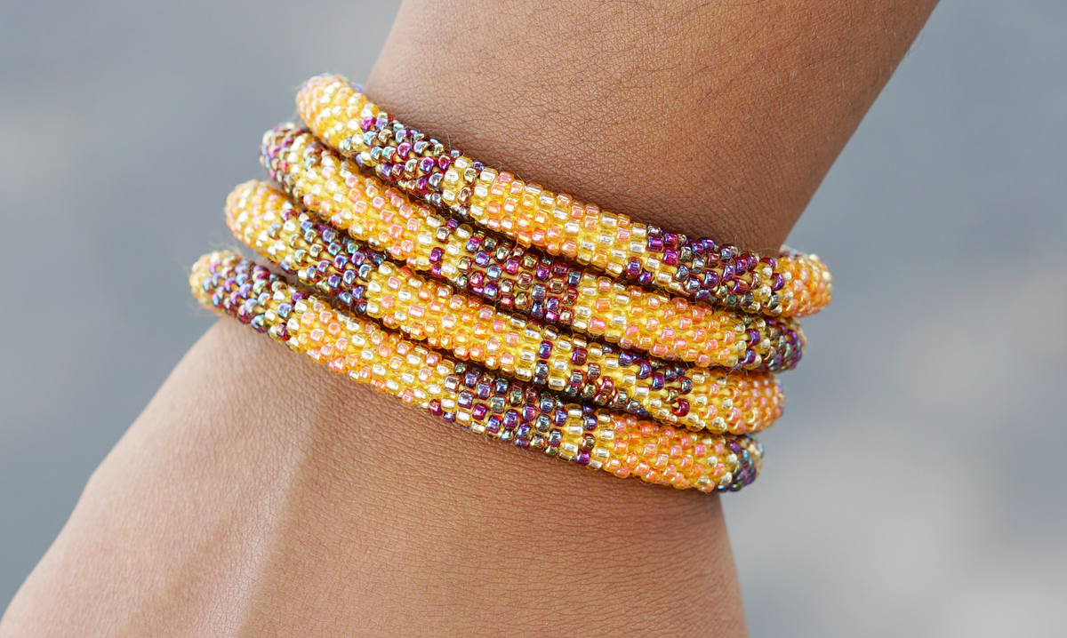 Sashka Co handmade beaded friendship bracelet with orange gold and iridescent glass beads. Crafted in Nepal by skilled artisans in a block spiral pattern.