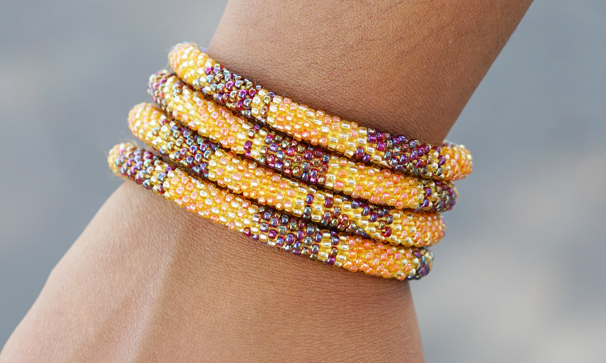 Sashka Co handmade beaded friendship bracelet with orange gold and iridescent glass beads. Crafted in Nepal by skilled artisans in a block spiral pattern.