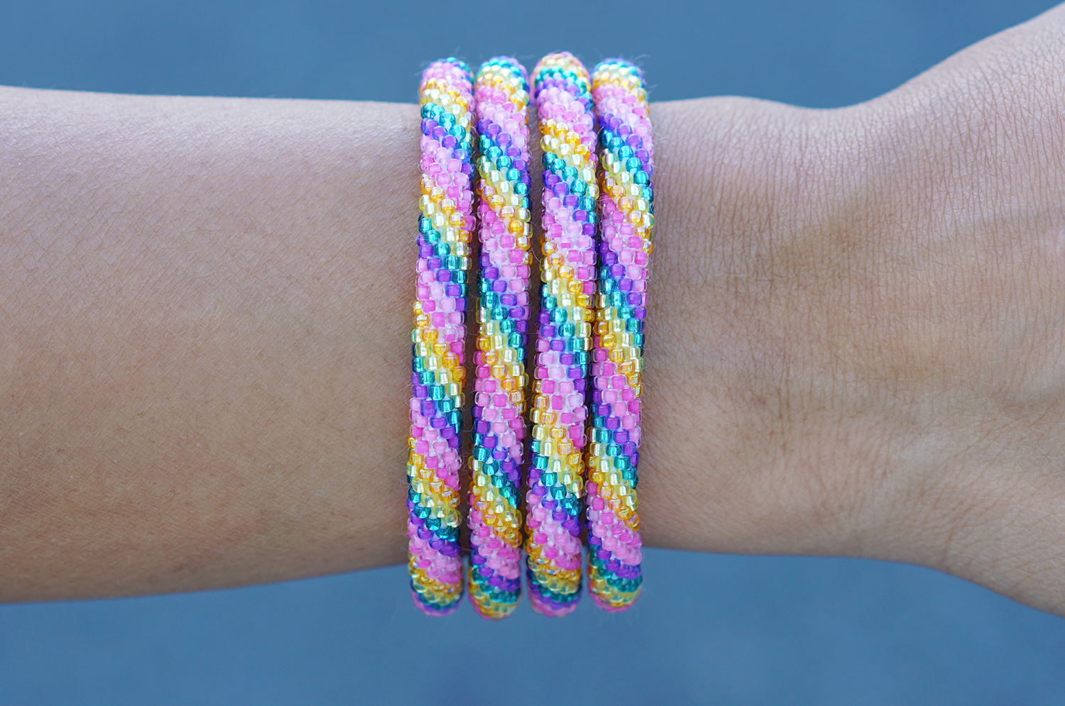 Sashka Co handmade beaded friendship bracelet with pink, purple, teal, yellow, and orange spiral pattern. Crafted in Nepal by skilled artisans.