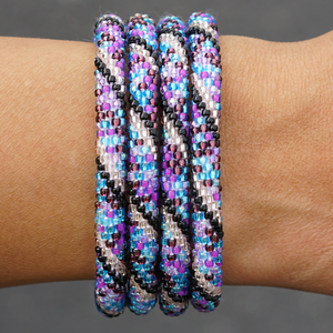 Sashka Co handmade beaded friendship bracelet with purple, black, blue, and rose gold glass beads. Crafted in Nepal by skilled artisans in a spiral mixed pattern.