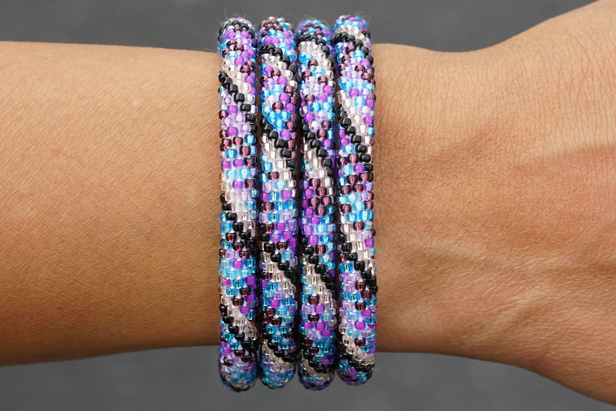 Sashka Co handmade beaded friendship bracelet with purple, black, blue, and rose gold glass beads. Crafted in Nepal by skilled artisans in a spiral mixed pattern.