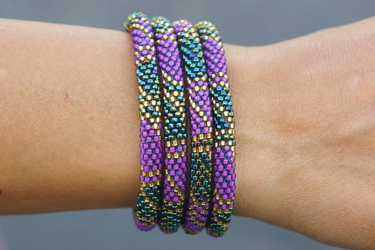 Sashka Co handmade beaded friendship bracelet with purple, gold, and iridescent glass beads. Crafted in Nepal by skilled artisans in a block spiral pattern.