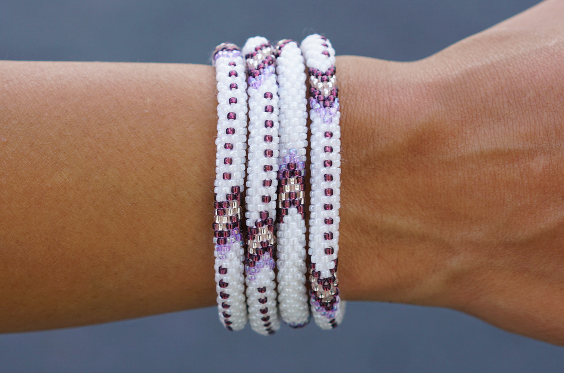 Sashka Co handmade beaded friendship bracelet with purple, white, and rose gold glass beads. Crafted in Nepal by skilled artisans in an arrow pattern.