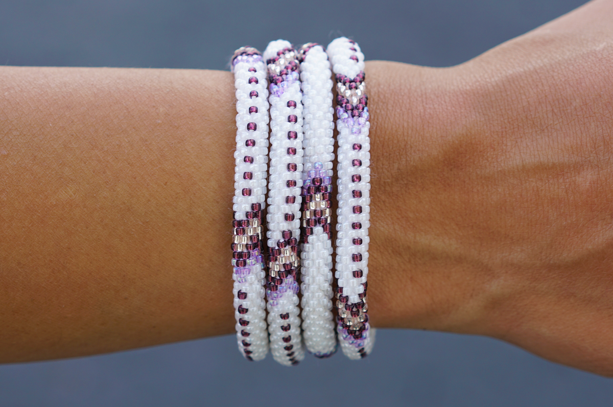 Sashka Co handmade beaded friendship bracelet with white, purple, and rose gold glass beads. Crafted in Nepal by skilled artisans in an arrow pattern.