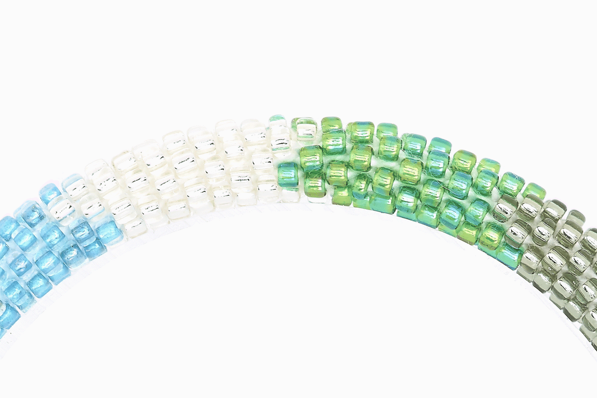 Sashka Co handmade beaded friendship bracelet with iridescent blue, silver, iridescent green, and clear glass beads. Crafted in Nepal by skilled artisans in a detailed chevron pattern.